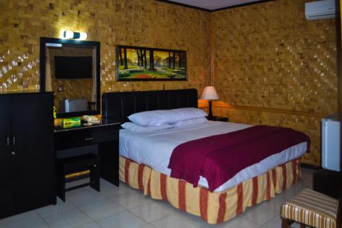 a bedroom with a bed and a desk and a television at Hotel Indra Toraja in Rantepao