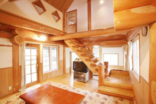 a living room with a spiral staircase in a log cabin at Kurokawa Mori no Cottage in Minamioguni
