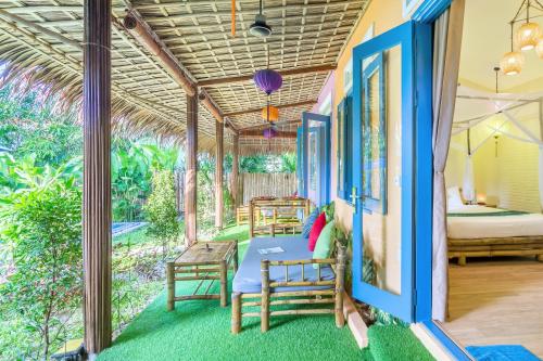 a room with a bed and chairs on a porch at An Bang beach Happy Village in Hoi An