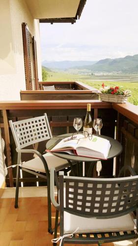 a table and chairs on a balcony with a bottle of wine at Haus Evi in Termeno