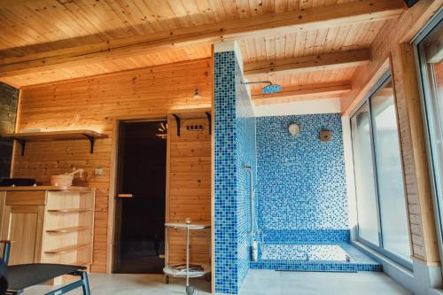 a bathroom with a shower with blue tiles on the wall at Wellness Chata Relax Ostružná in Ostružná