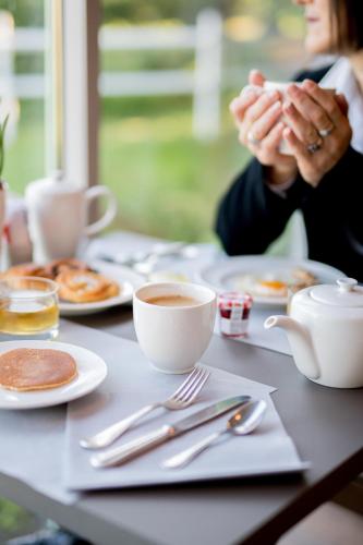 a table with plates of food and cups of coffee at Logis Hôtels- Hôtel et Restaurant Domaine de Fompeyre in Bazas