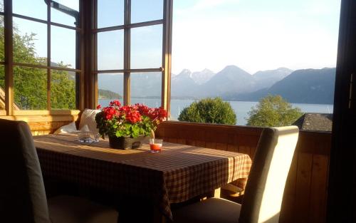 a table with a vase of flowers on a balcony at Sonnwirtstöckl am See in Sankt Gilgen