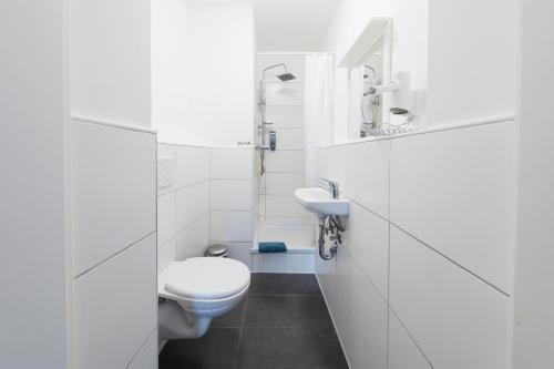a white bathroom with a toilet and a sink at Berolina Haus in Düsseldorf