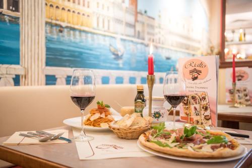 a table with two glasses of wine and a pizza at Hotel Esplanade & Aparthotel Rialto in Binz