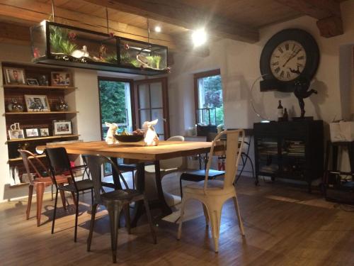 uma sala de jantar com uma mesa com cadeiras e um relógio em LaMaisonRouge chambre d'hôtes em Cormondreche