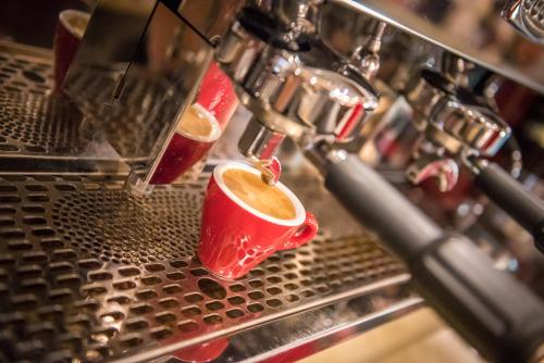 two cups of coffee are being made in a espresso machine at Hotel Esplanade & Aparthotel Rialto in Binz
