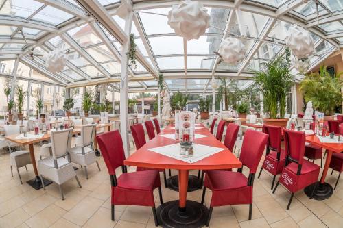 a restaurant with red tables and chairs and a glass ceiling at Hotel Esplanade & Aparthotel Rialto in Binz