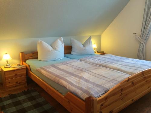 sypialnia z dużym drewnianym łóżkiem z białymi poduszkami w obiekcie Ferienwohnung Morgensonne w Prerowie