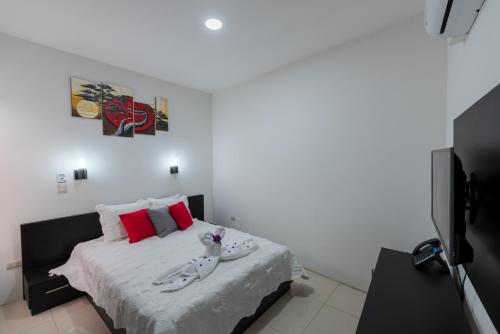 a white bedroom with a bed with red pillows at Apartamentos La Casona in Fortuna