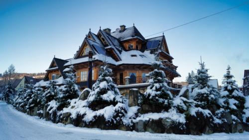 a large wooden house covered in snow at Willa Tatrzański Zomecek in Kościelisko