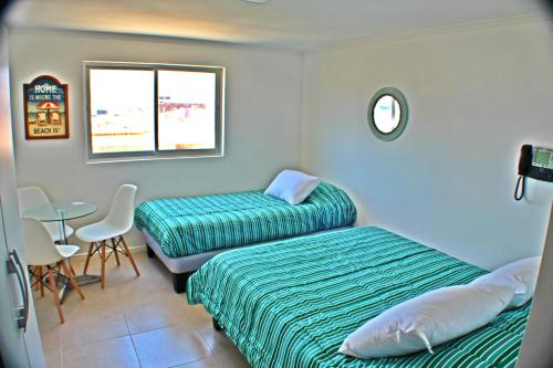 a room with two beds and a table and a window at Playa Hotel - Cavancha in Iquique