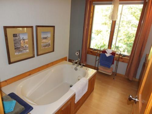 a large bath tub in a bathroom with two windows at Agape Bayside Cottage in Frankfort