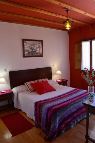a bedroom with a large bed with red pillows on it at Hospedium Hostal Almanzor in Navarredonda de Gredos