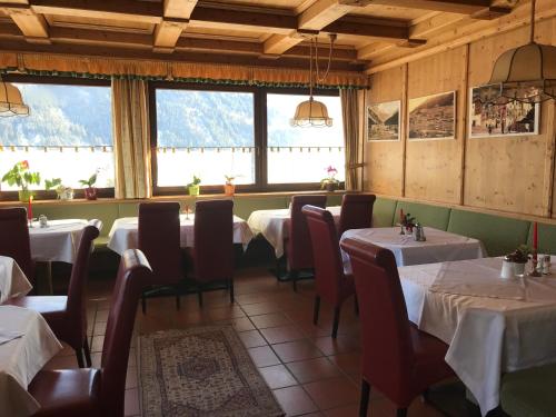 un comedor con mesas, sillas y ventanas en Hotel Pension Weiratherhof, en Wenns