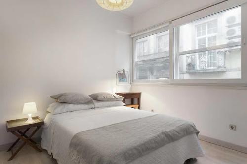 een witte slaapkamer met een bed en 2 ramen bij white fabrica house in Porto