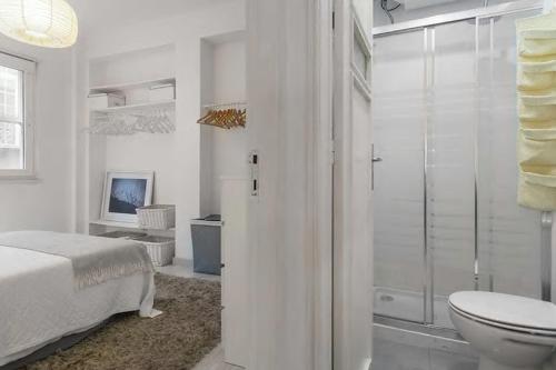 een slaapkamer met een bed en een badkamer met een douche bij white fabrica house in Porto