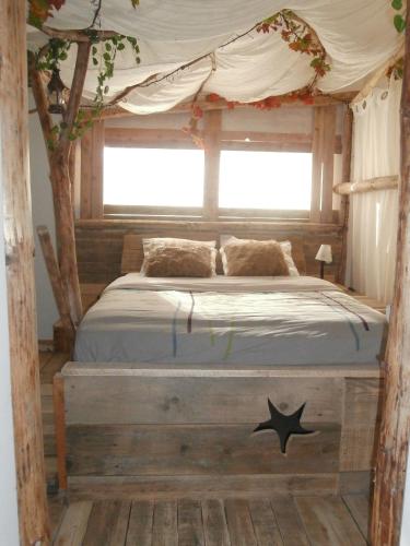 a bed with a canopy in a room with a window at le Crusoé à l'étang d'Anty -chambre d'hôtes in Saint-Nabord