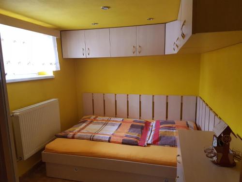 ein Schlafzimmer mit einem Bett mit gelben Wänden und einem Fenster in der Unterkunft Apartment Alta in Liptovský Mikuláš