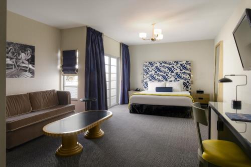 a hotel room with a bed and a couch at Hotel Breakwater South Beach in Miami Beach