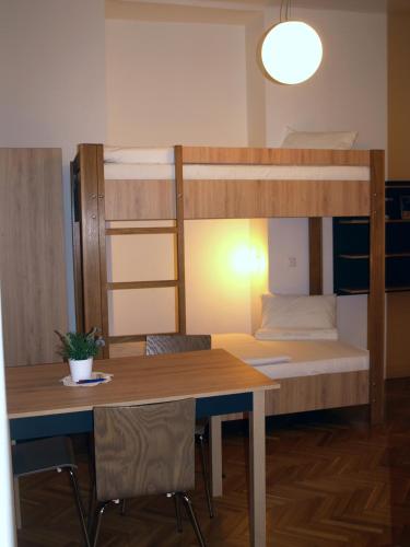 a room with a table and a bunk bed at Ciszterci Szállás Pécs in Pécs