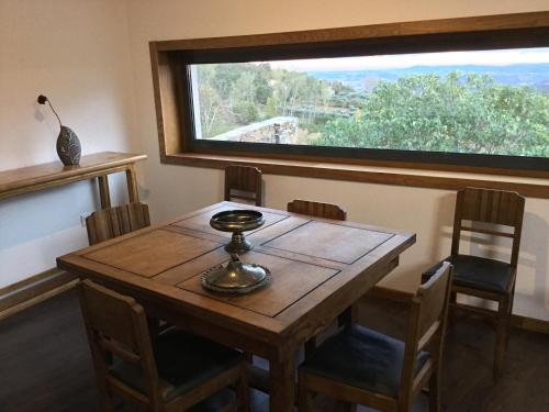 uma mesa de madeira e cadeiras num quarto com uma janela em Casas do Bairrinho em Sambade