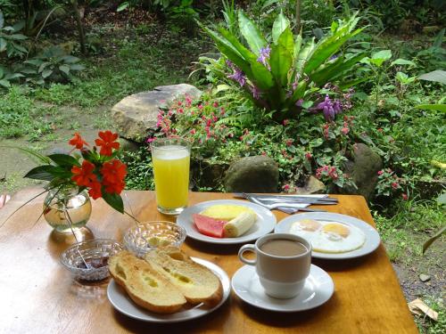 a table with eggs and toast and a cup of orange juice at Cabañas Armonía y Jardín de Orquídeas in Mindo