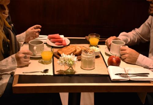 Esplendor by Wyndham Buenos Aires في بوينس آيرس: شخصان يجلسان على طاولة مع صينية طعام