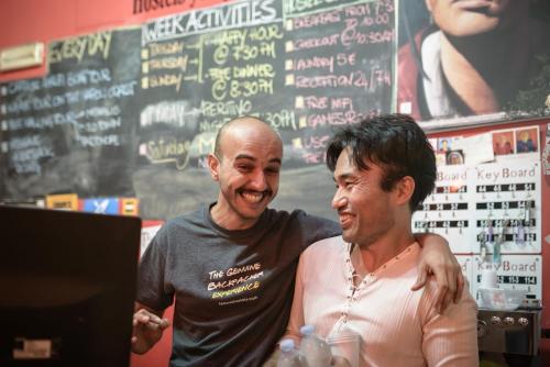 two men standing in front of a laptop computer at Hostel of the Sun in Naples