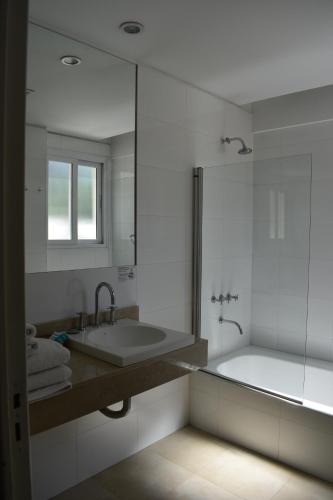a bathroom with a tub and a sink and a mirror at Hotel Cervantes in Mendoza