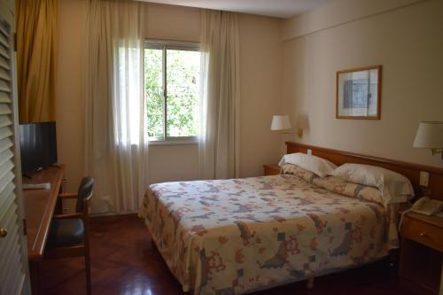 a hotel room with a bed and a window at Hotel Cervantes in Mendoza