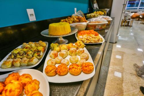 a buffet with several plates of food on a counter at Mega Moda Goiania Hotel in Goiânia