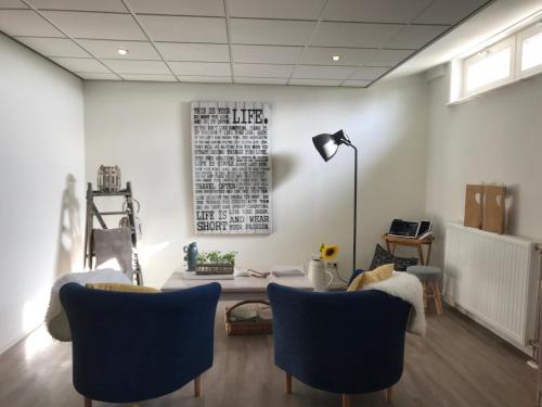 a living room with blue chairs and a table at De Beddestee in Ruinen