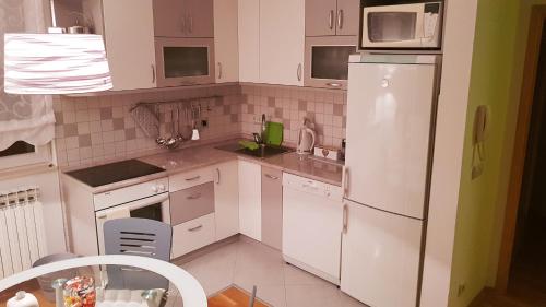 a kitchen with white cabinets and a white refrigerator at Apartment Dominik in Osijek