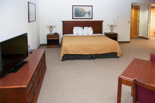 a hotel room with a bed and a flat screen tv at Alex Hotel and Suites in Anchorage