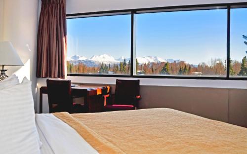 a hotel room with a bed and a desk and a large window at Alex Hotel and Suites in Anchorage