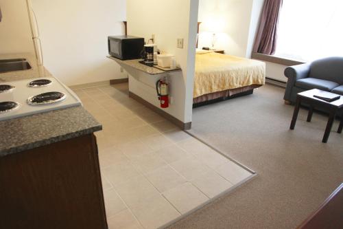 a hotel room with a bed and a kitchen with a stove at Alex Hotel and Suites in Anchorage