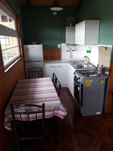 a kitchen with a table and a stove and a stove top at Cabañas Lago Tyndall in Torres del Paine