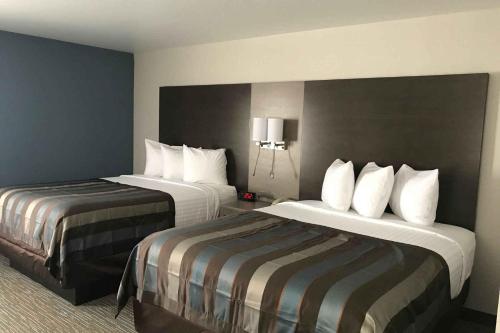 a hotel room with two beds with white pillows at Wingate by Wyndham Louisville Airport Expo Center in Louisville
