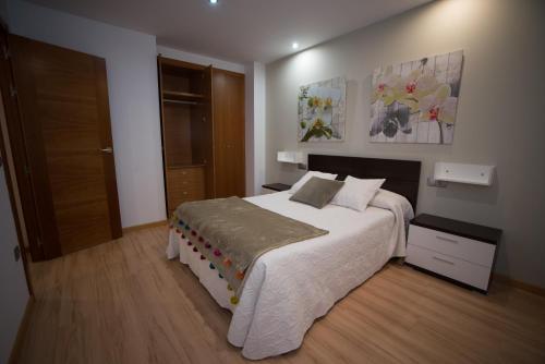 - une chambre avec un grand lit blanc et des peintures murales dans l'établissement Almudena, à Teruel