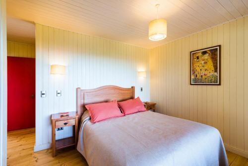 a bedroom with a large bed with two pink pillows at Cabañas Cantomar in Pichilemu