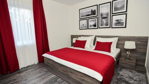 sypialnia z dużym łóżkiem z czerwoną pościelą i poduszkami w obiekcie Sunset Deluxe Apartments w mieście Vir