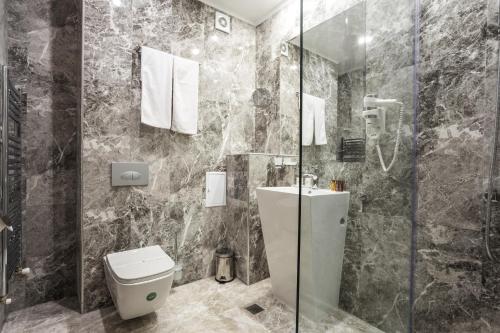 a bathroom with a toilet a sink and a shower at Earth & People Hotel & SPA in Sofia
