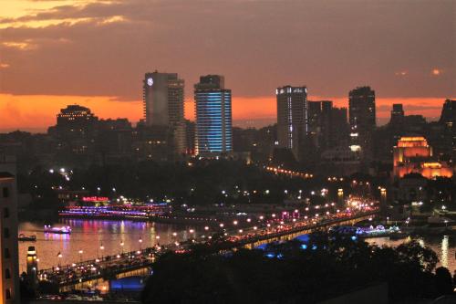 um horizonte da cidade à noite com um rio e edifícios em Cleopatra Hotel no Cairo