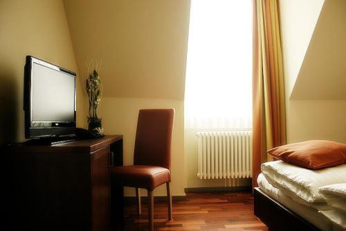 a bedroom with a desk with a television and a chair at Hotel am Kulturplatz in Rastatt