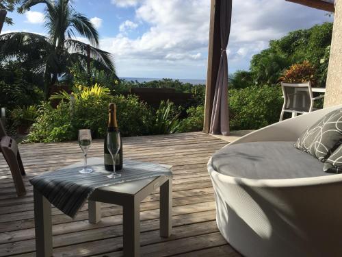 a bottle of wine sitting on a table on a deck at Ali-Naïs Location in Deshaies