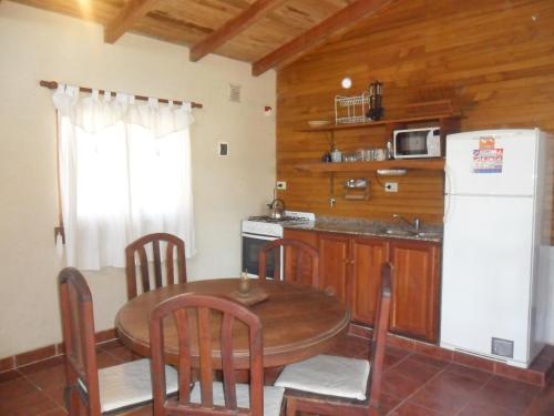 Una cocina con una mesa y un refrigerador blanco. en Cabañas del Dique Frente al Lago, en Villa del Dique