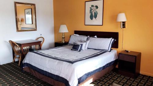 ein Hotelzimmer mit einem großen Bett und einem Spiegel in der Unterkunft Village Inn Salina in Salina