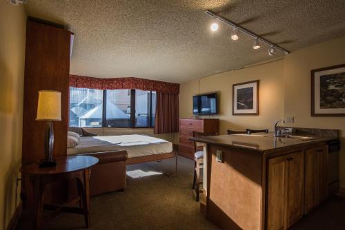 The Grand Lodge Hotel and Suites في Mount Crested Butte: غرفة بسرير ومطبخ مع حوض