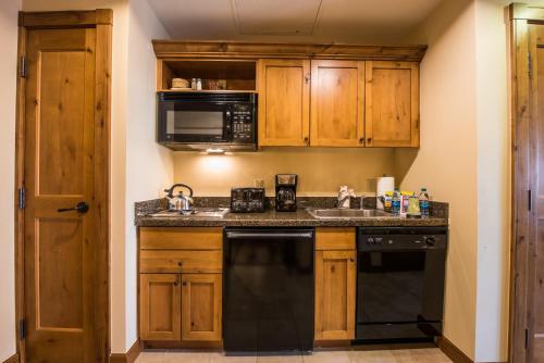 a kitchen with wooden cabinets and a black dishwasher at The Lodge at Mountaineer Square in Mount Crested Butte
